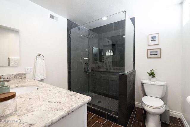 bathroom with toilet, a shower with shower door, and vanity