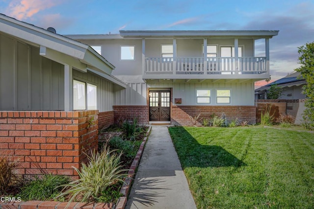 view of front of property featuring a yard, french doors, and a balcony