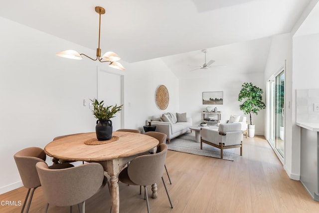 dining area with lofted ceiling, ceiling fan with notable chandelier, and light hardwood / wood-style flooring