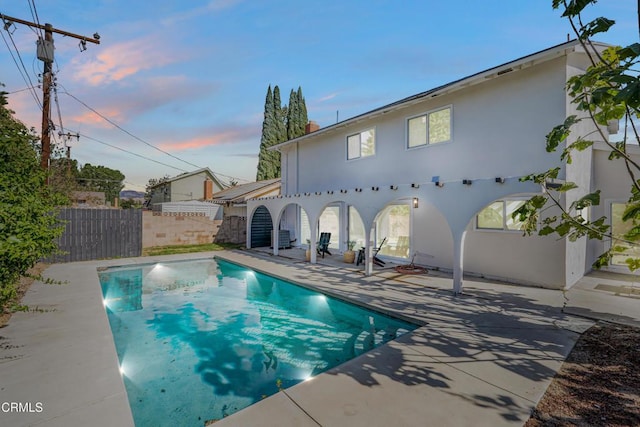 pool at dusk featuring a patio