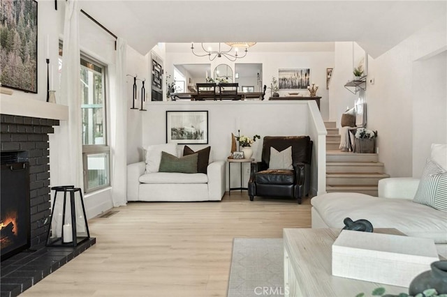 living room featuring light hardwood / wood-style flooring, a notable chandelier, and a fireplace