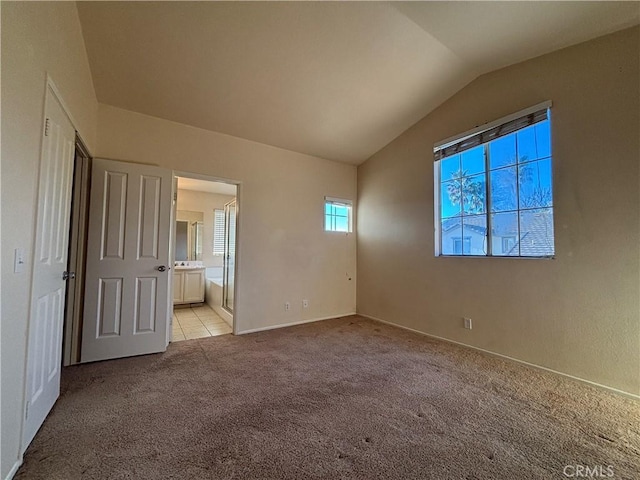 unfurnished bedroom featuring light carpet, vaulted ceiling, and connected bathroom