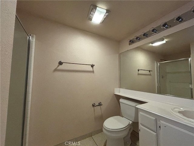 bathroom featuring toilet, vanity, tile patterned flooring, and a shower with door