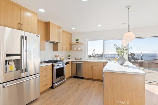 kitchen with pendant lighting, appliances with stainless steel finishes, light brown cabinetry, sink, and light wood-type flooring