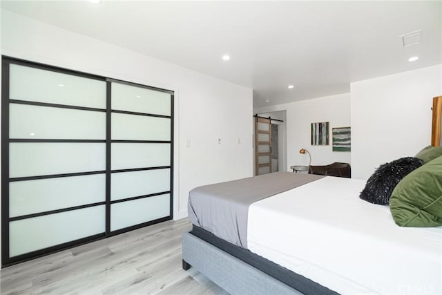 bedroom featuring light hardwood / wood-style floors and a barn door