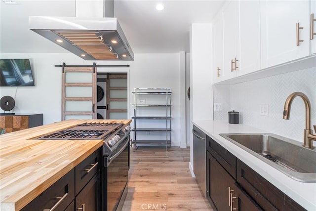 kitchen with a barn door, stacked washer and dryer, appliances with stainless steel finishes, and butcher block countertops