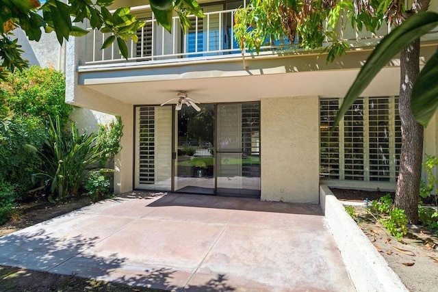 entrance to property with a balcony, a patio area, and ceiling fan