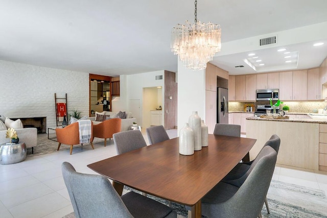 tiled dining room with a fireplace and a notable chandelier