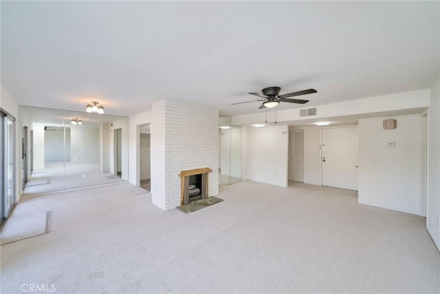 unfurnished living room featuring ceiling fan, a brick fireplace, and light carpet