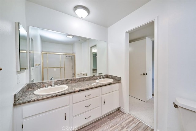 bathroom featuring hardwood / wood-style floors, toilet, a shower with door, and vanity