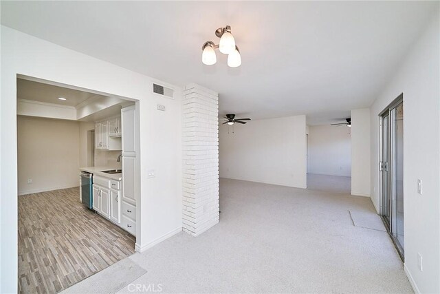 interior space with stainless steel dishwasher, white cabinets, sink, a raised ceiling, and light colored carpet