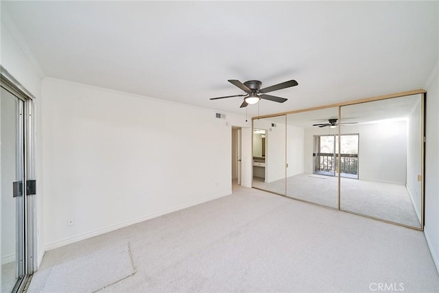 unfurnished bedroom featuring a closet, ceiling fan, light colored carpet, and crown molding