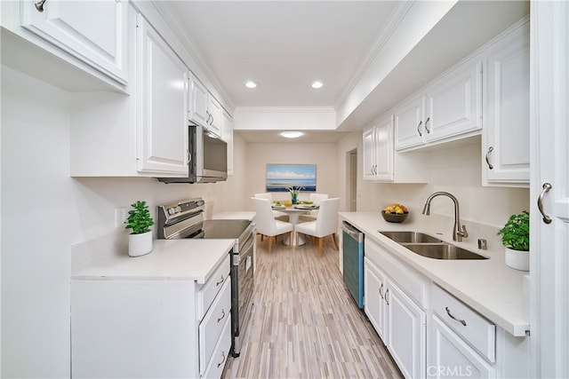 kitchen featuring crown molding, appliances with stainless steel finishes, sink, white cabinets, and light hardwood / wood-style flooring