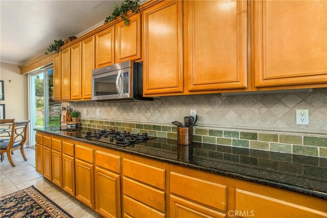 kitchen featuring light tile patterned floors, backsplash, black gas cooktop, and dark stone counters