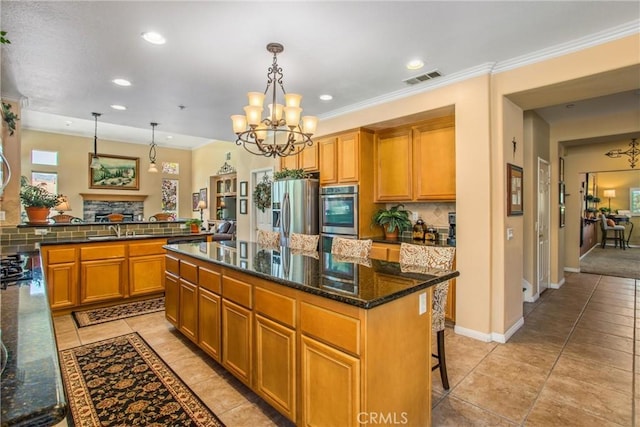 kitchen with a notable chandelier, pendant lighting, a kitchen island, a kitchen bar, and stainless steel appliances