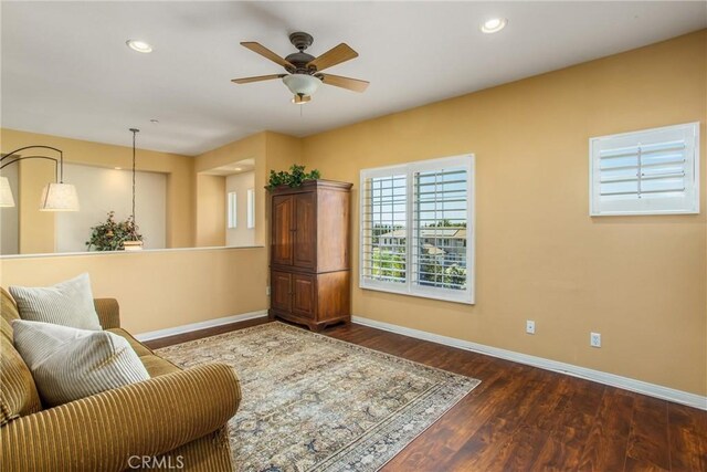 living room featuring ceiling fan and dark hardwood / wood-style floors