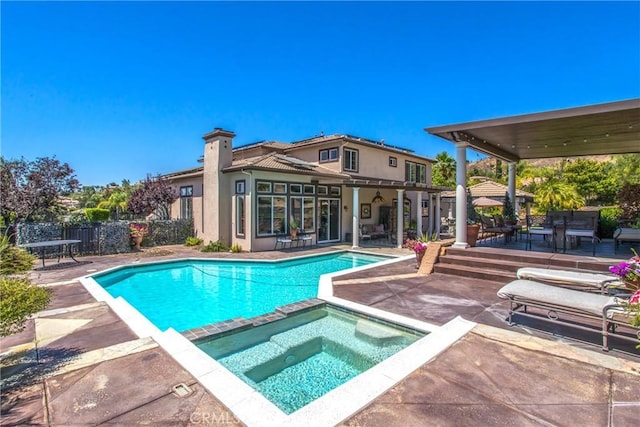 view of pool with a pool with connected hot tub, a patio area, and fence