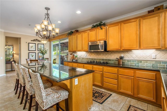 kitchen featuring a kitchen bar, black gas cooktop, decorative light fixtures, a notable chandelier, and a kitchen island