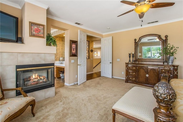 sitting room featuring ceiling fan, light colored carpet, ornamental molding, and a fireplace