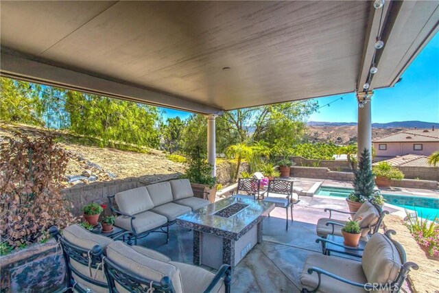 view of patio / terrace with a fenced in pool and an outdoor living space with a fire pit