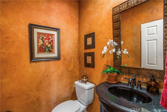 bathroom with backsplash, toilet, and vanity