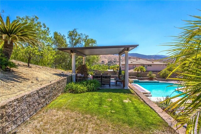 view of swimming pool with a mountain view, a patio area, and a yard