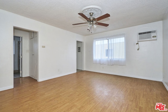 unfurnished room with a textured ceiling, light hardwood / wood-style flooring, and a wall mounted AC