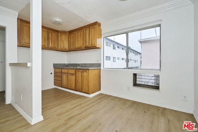 kitchen featuring a textured ceiling, light hardwood / wood-style flooring, and crown molding