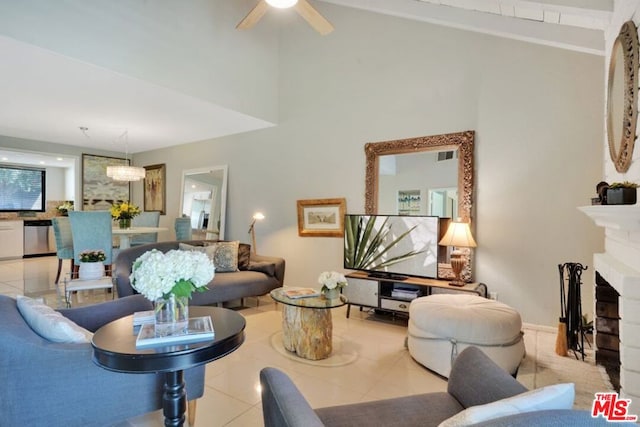 living room featuring a brick fireplace, ceiling fan, and light tile patterned flooring