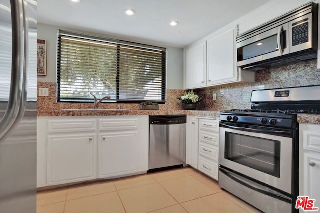 kitchen with light tile patterned floors, appliances with stainless steel finishes, white cabinets, and sink