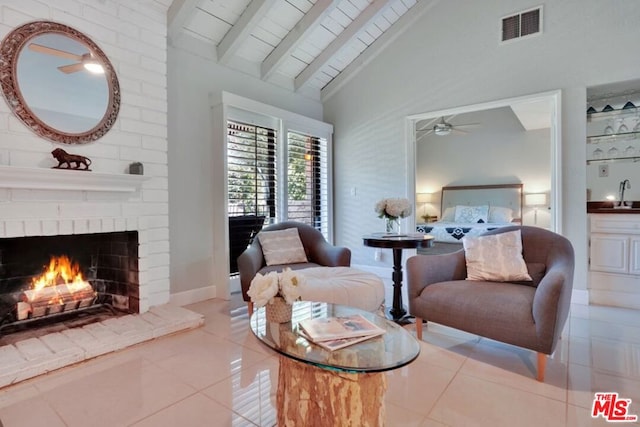 living area with ceiling fan, a brick fireplace, lofted ceiling with beams, sink, and light tile patterned flooring