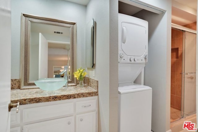 washroom featuring stacked washing maching and dryer and sink