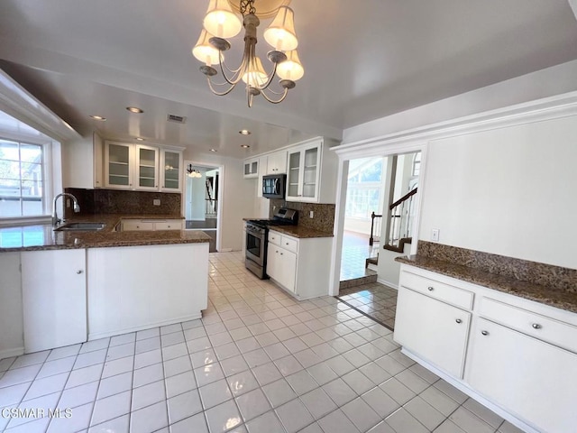 kitchen with stainless steel range with gas cooktop, hanging light fixtures, white cabinets, and sink