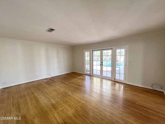 spare room with hardwood / wood-style floors, crown molding, and french doors