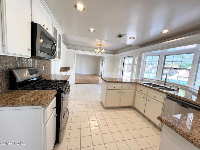 kitchen with decorative backsplash, sink, an inviting chandelier, appliances with stainless steel finishes, and white cabinets