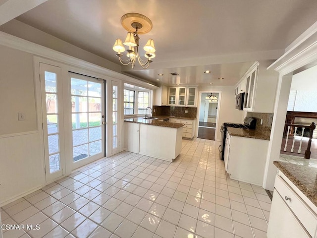 kitchen with light tile patterned floors, gas range gas stove, pendant lighting, and white cabinetry