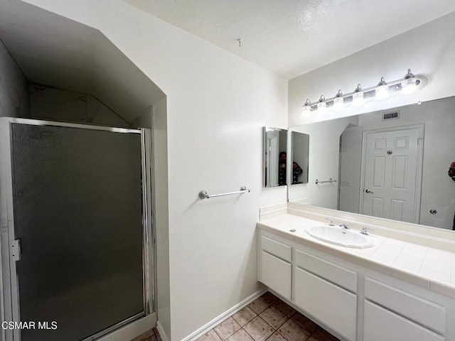 bathroom featuring a shower with shower door, vanity, and tile patterned flooring