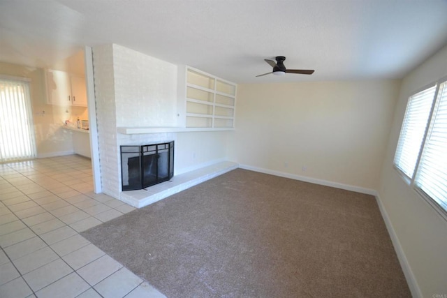 unfurnished living room featuring ceiling fan, built in shelves, and tile patterned floors