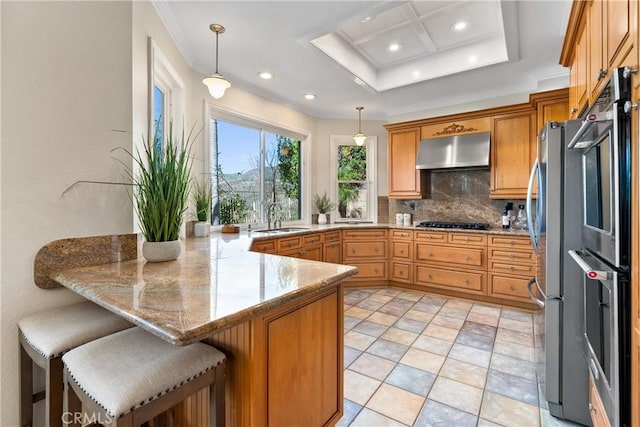 kitchen featuring a kitchen breakfast bar, hanging light fixtures, kitchen peninsula, and exhaust hood