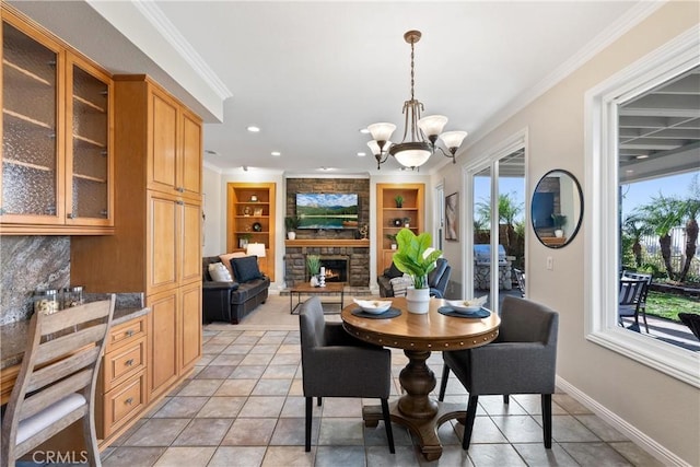 dining space featuring a fireplace, built in features, a chandelier, light tile patterned floors, and crown molding