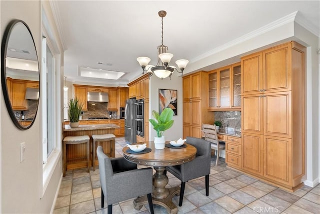 tiled dining room featuring built in desk, crown molding, a tray ceiling, and a chandelier