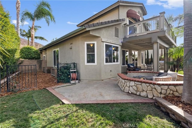 rear view of house featuring a balcony, a patio area, and a lawn