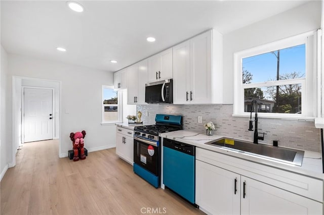 kitchen with white cabinetry, stainless steel appliances, tasteful backsplash, sink, and light wood-type flooring