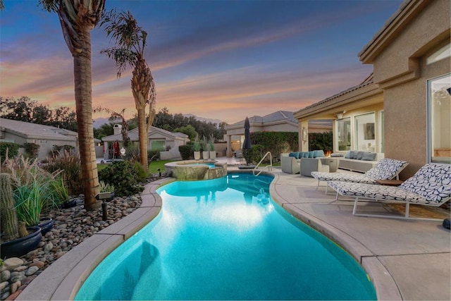 pool at dusk with an in ground hot tub, a patio area, and an outdoor living space