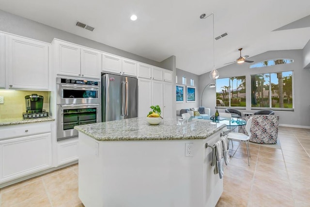 kitchen featuring decorative light fixtures, white cabinetry, stainless steel appliances, and a kitchen island