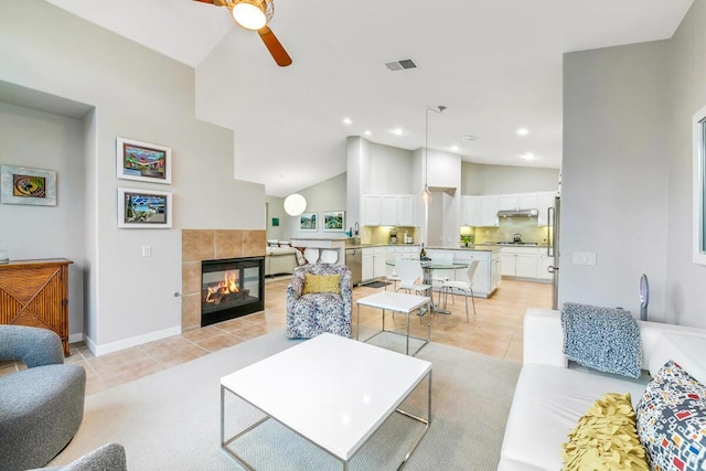 living room featuring ceiling fan, light tile patterned floors, a fireplace, and high vaulted ceiling