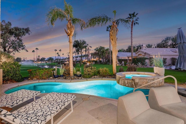 pool at dusk featuring a patio area and an in ground hot tub