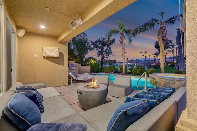 patio terrace at dusk featuring a pool with hot tub and an outdoor fire pit