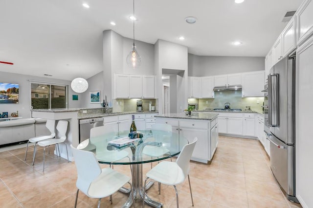 kitchen featuring kitchen peninsula, appliances with stainless steel finishes, decorative light fixtures, white cabinets, and a center island