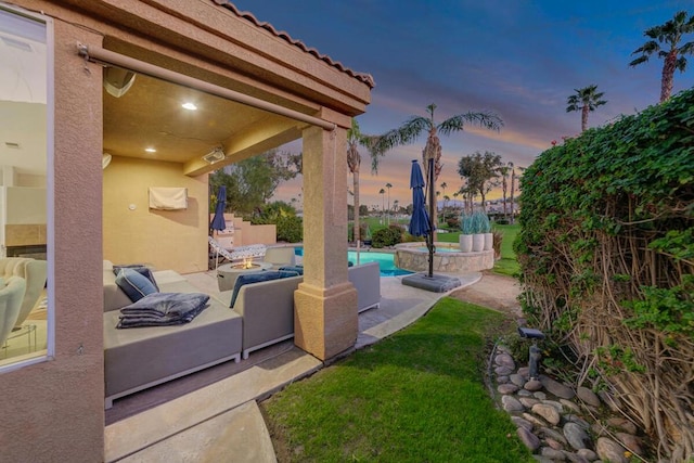 patio terrace at dusk featuring a swimming pool with hot tub and a fire pit